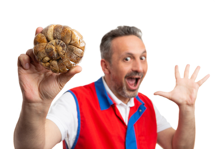 Closeup of dried figs held by surprised male hypermarket or supermarket employee making gesture with hands and expression in background isolated on whiteの写真素材