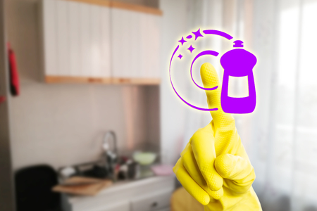 Person with yellow latex gloves touching dish-soap symbol on transparent display using index fingerの写真素材