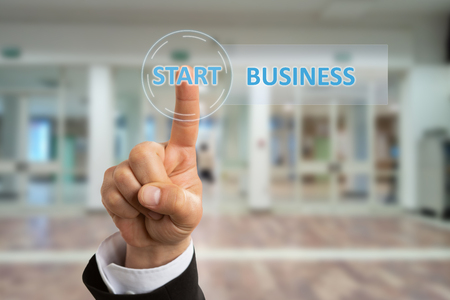 Businessman wearing suit touching start business button with index finger on invisible background...