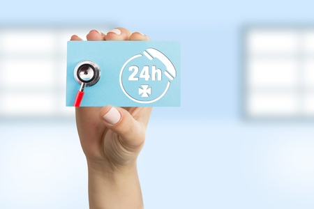 Female doctor showing blue paper card with stethoscope and telephone symbol as contact and non-stop call center conceptの写真素材