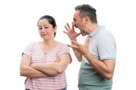 Annoyed man making angry gesture and shouting at woman with indifferent expression isolated on white backgroundの写真素材