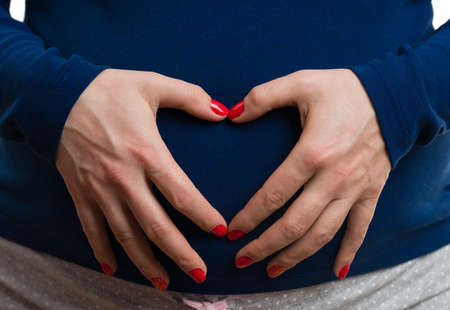 Smiling pregnant woman holding string with ultrasound pictures and red heart as love concept...