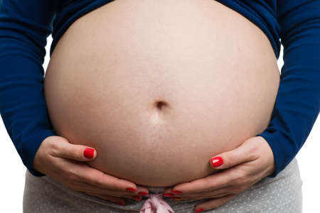 Close-up of future mom grabbing her tummy isolated on white studio background as caring mother conceptの写真素材