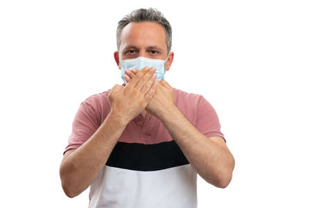 Adult male covering mouth with coronavirus pandemic protection face mask and hands as quiet secret...