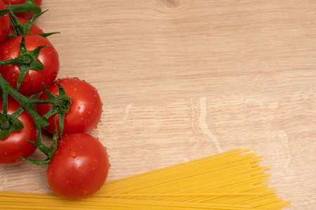 Italian pasta spaghetti and juicy organic tomatoes close-up with blank copyspace for advertising text on cutting board as fresh cooking conceptの写真素材