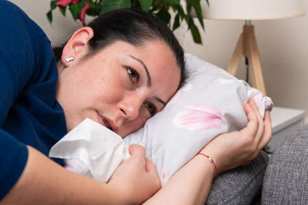 Adult female model with sick tired expression as covid10 sars influenza virus fatigue symptom laying...