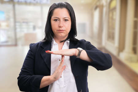 Female entrepreneur businesswoman with serious expression making timeout pause gesture using fingers as leadership conceptの写真素材