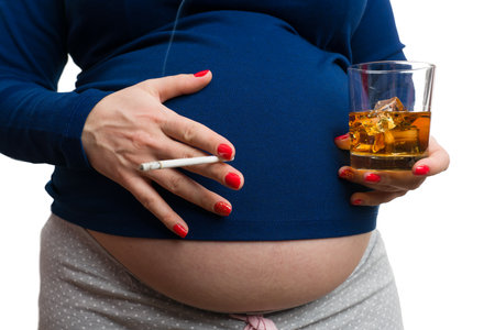 Close-up of pregnant woman holding cigarette and whiskey isolated on white background as unhealthy pregnancy conceptの写真素材