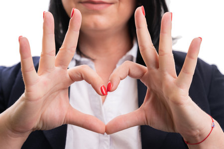 Close-up of heart symbol made by adult entrepreneur woman in formalwear as love business corporation concept isolated on white studio backgroundの写真素材