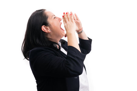 Businesswoman in formalwear smart suit shouting with hands around mouth at blank copyspace for advertising isolated on white backgroundの写真素材