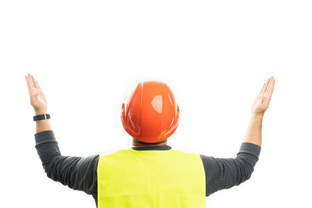 Adult male builder wearing orange safety hardhat and vest with back to camera presenting blank...