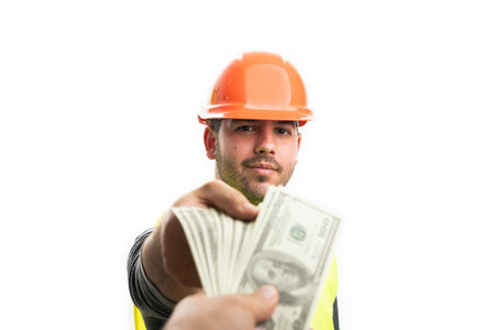 Friendly trustworthy builder man in work attire with happy smiling expression receiving cash money as wage salary concept isolated on white backgroundの写真素材