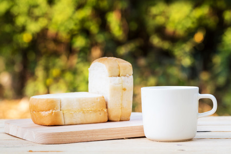 Coffee cup and bread on wooden floor with blurry bokeh background
