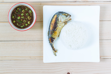 Fried short mackerel fishes with rice and chili paste on wooden floorの写真素材