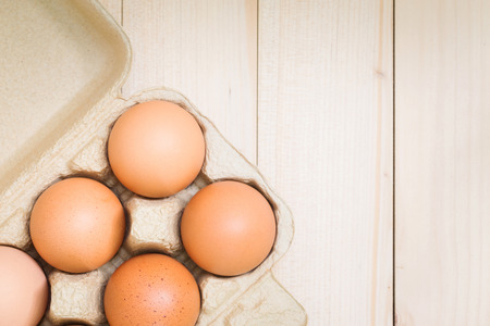 Eggs in a carton on a wooden table topの写真素材