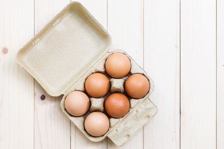 Eggs in a carton on a wooden table topの写真素材