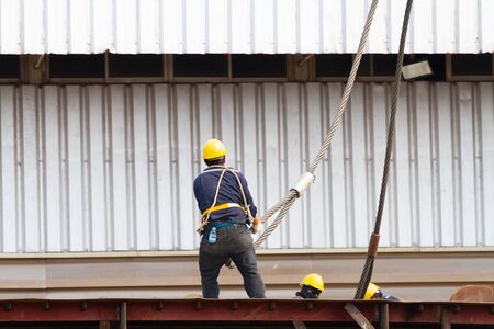 Worker pulling heavy duty steel wire rope at construction site