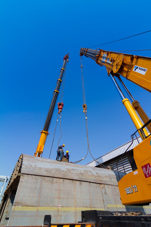 TWo truck cranes working over dry dock are lifting ship hull partのeditorial素材