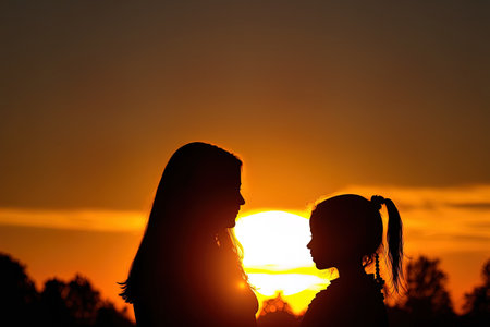 Sunset with a silhouette of a woman and her daughter standingの素材