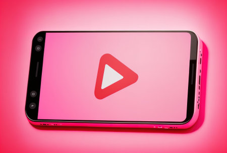 On a pink backdrop, a smartphone or mobile phone with the YouTube emblem shownの素材