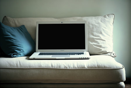 At home, a laptop with a white blank screen is on a sofa.の素材