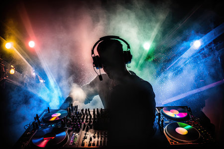 Club dj using headphones and a mixer. An ambient laser light showの素材