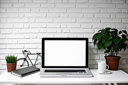 Hipster designer or artist desk work in a loft a white table with craft supplies a laptop with a blank screen and a dummy against a vintage brick wall. Blank screen for showing montage of graphicsの素材