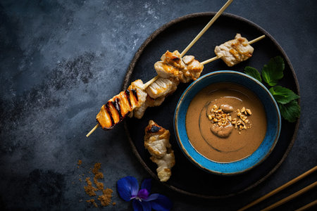 Satay chicken with peanut sauce. A peanut dipping sauce is provided with the grilled chicken skewers. Dinner or party appetizers that are delicious. Background of blue stone with blank text space. froの素材