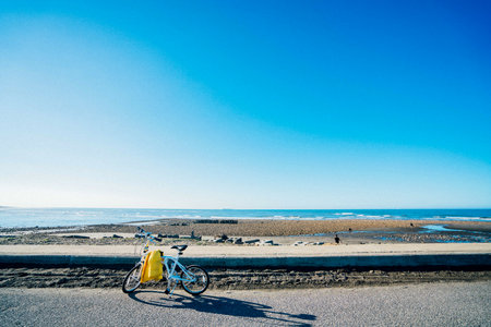 Bicycle on the beach with blue sky and sea in background.の写真素材