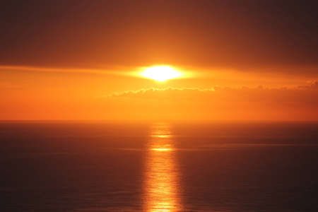 Sunset in progress through cloudsの写真素材