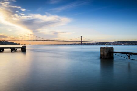View of the bridge over the Tagus River in Lisbon, Portugal, at sunsetの写真素材