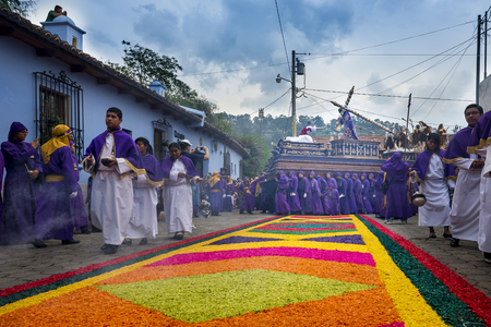 Antigua, Guatemala - April 16, 2014: Man wearing purple and white robes, carrying a float (anda)...