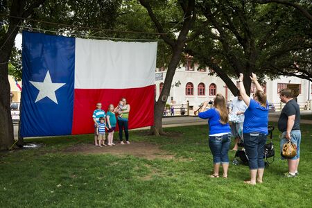Fort Worth, Texas, USA - June 10, 2014: Family taking a photo in front of the Texas Flag in the Fort Worth Stockyards, Forth Worth, Texasのeditorial素材