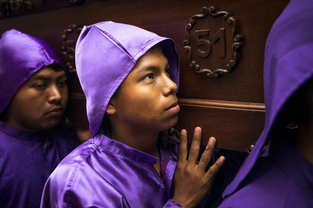 Antigua, Guatemala - April 16, 2014: Man wearing purple robes, carrying a float (anda) during the Easter celebrations, in the Holy Week, in Antigua, Guatemala.のeditorial素材