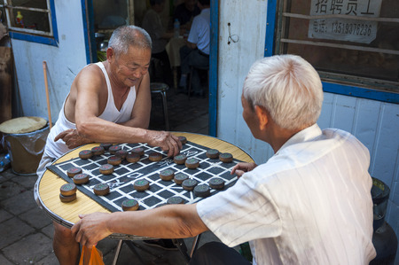 Dunhuang, China - August 7, 2012: Two Chinese man playing Chinese Chess (Xiangqi) in a street of the city of Dunhuang, Chinaのeditorial素材