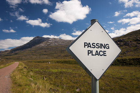A Passing Place road sign in a narrow country road in the Highlands of Scotland, United Kingdom; Concept for driving in country roads in the United Kingdomの写真素材
