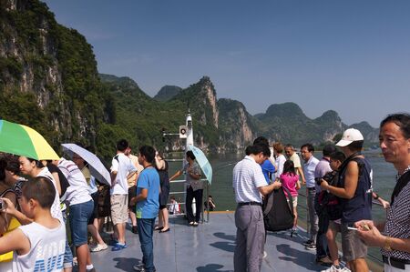 Yangshuo, China - August 1, 2010: People in a boat cruising in the Li River and looking at the the tall limestone mountains near Yangshuo in China, Asia.のeditorial素材