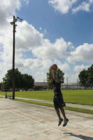 New Orleans, Louisiana - June 16, 2014: Young man training basketball in a street court in the city...