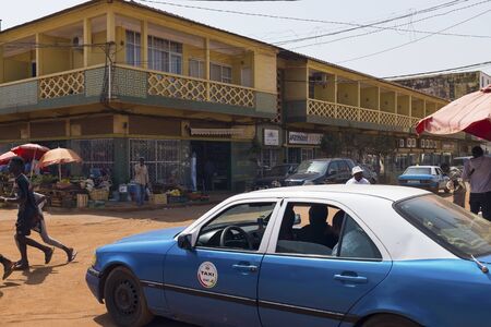 Bissau, Guinea Bissau - January 30, 2018: Street scene in the city of Bissau with a taxi and people crossing a dirt road, in Guinea Bissau, West Africaのeditorial素材