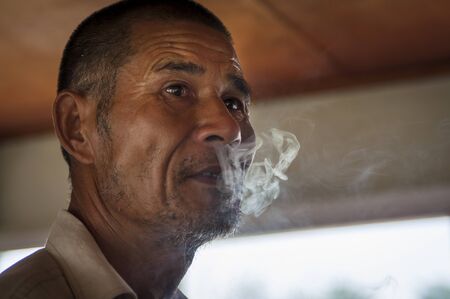 Yangshuo, China - August 2, 2012: Portrait of a Chinese man smoking a cigarette in a boat in the Li River near the town of Yangshuo, in China.のeditorial素材