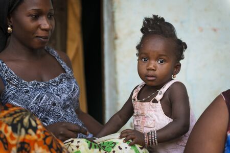 Bissau, Republic of Guinea-Bissau - January 31, 2018: Portrait of a mother and her baby daughter at the Cupelon de Cima neighborhood in the city of Bissau, Guinea Bissau.のeditorial素材
