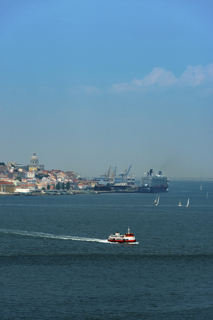 View of the skyline of the city of Lisbon with a traditional passenger boat (cacilheiro) on the Tagus River; Concept for travel in Portugal and visit Lisbonの写真素材