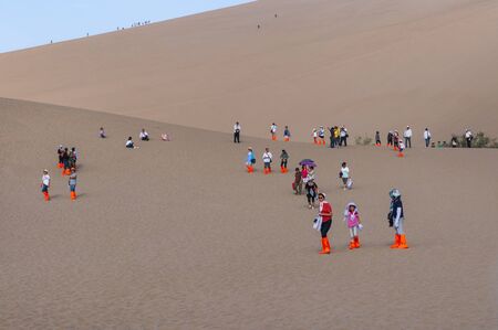 Dunhuang, China - August 8, 2012: Group of Chinese tourists at the Crescent Moon Lake near the city of Dunhuang, in the Gansu Province, China.のeditorial素材