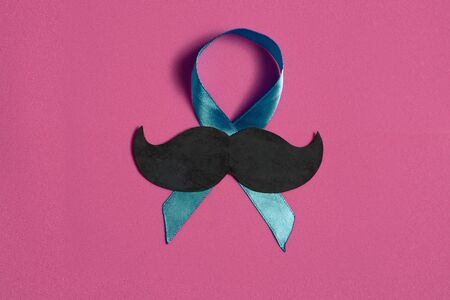 Moustache and blue ribbon on pink isolated background, international cancer prostate day concept, with copy spaceの写真素材