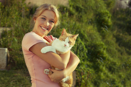 Beautiful blond young woman with ginger catの写真素材