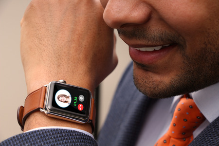Businessman taking a call on his smart watchの写真素材