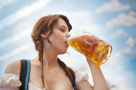 Young German woman drinking beer inside a tent at Oktoberfestの写真素材