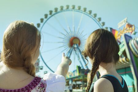 German girls going to big ferris wheel at Oktoberfestの写真素材