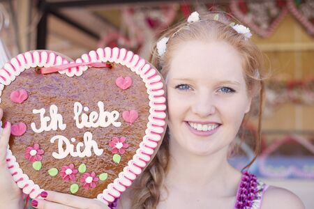 German girl holding a traditional Oktoberfest's gingerbread heartの写真素材
