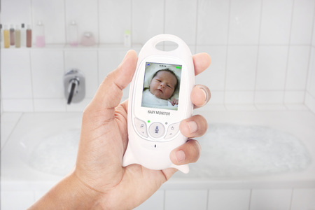 Mother checking newborn through baby monitor shortly before she takes a bathの写真素材